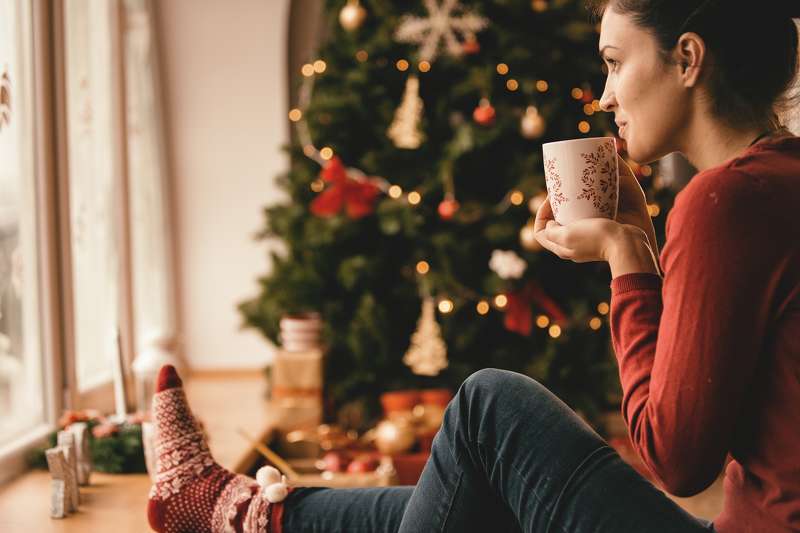 Woman drinking tea by the Christmas tree